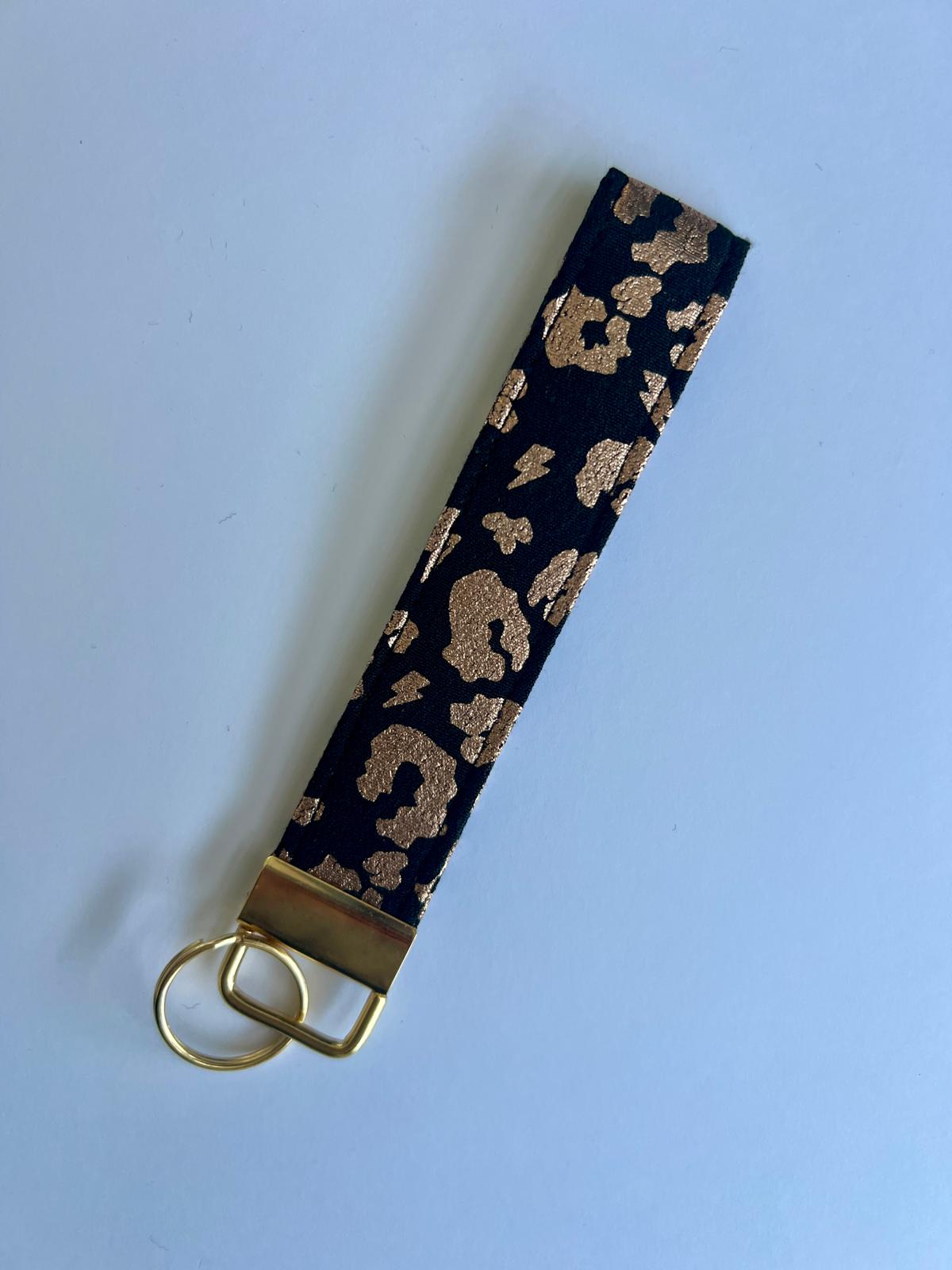 Keychain with metallic gold leopard print strap on a black background