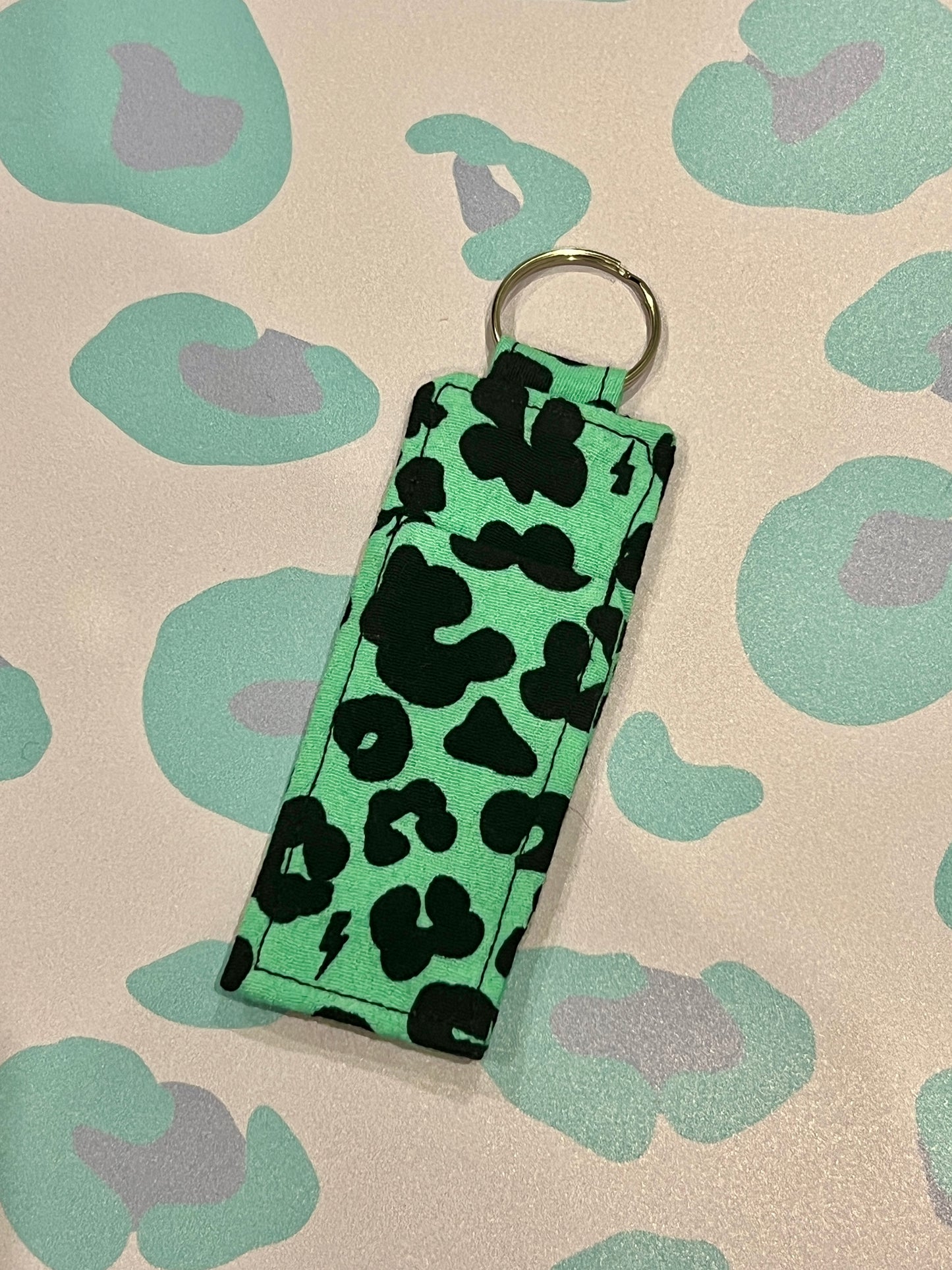Keychain with green and black pattern on a beige background with green and purple shapes