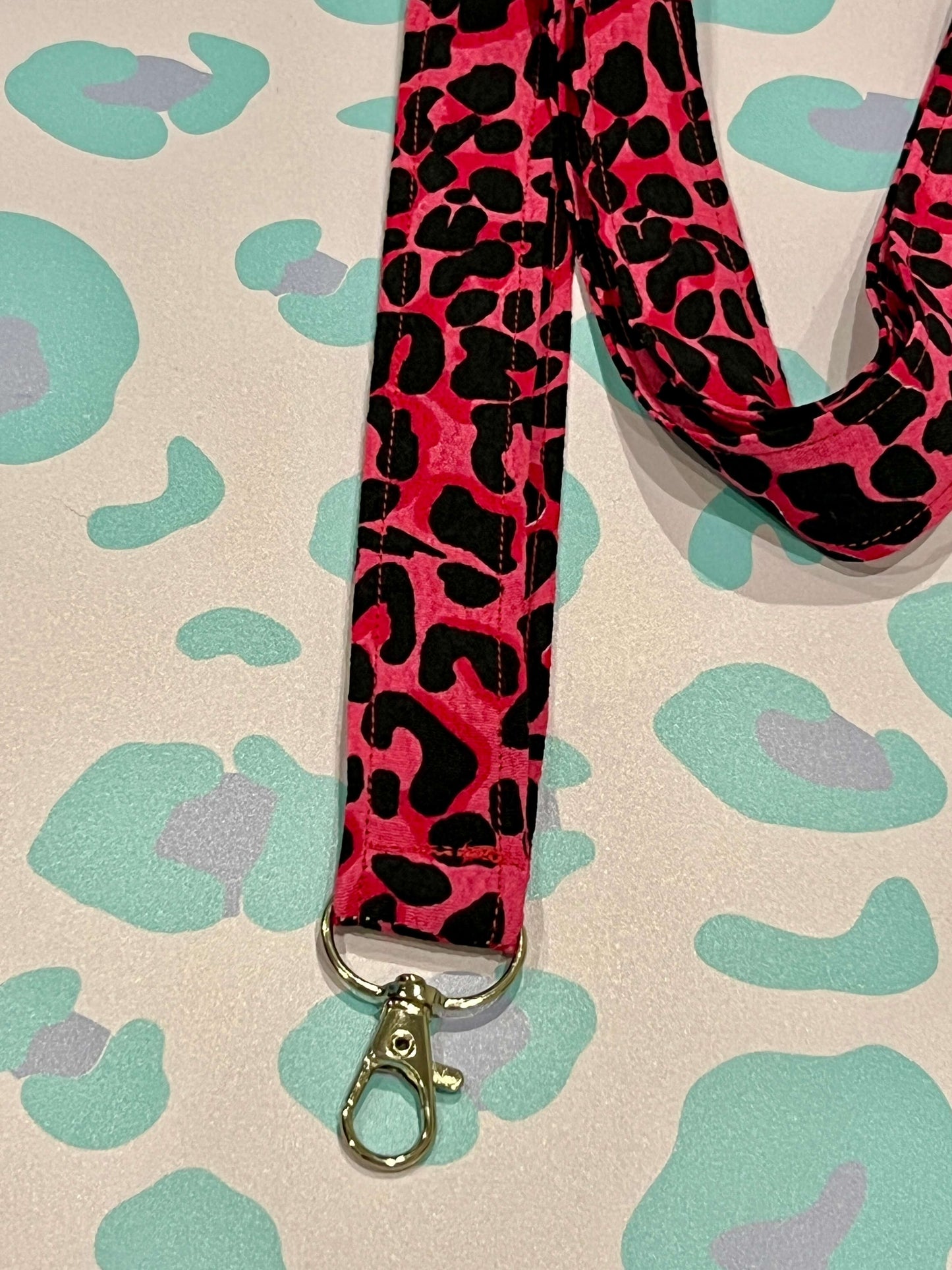 Pink and black leopard print lanyard on a patterned background