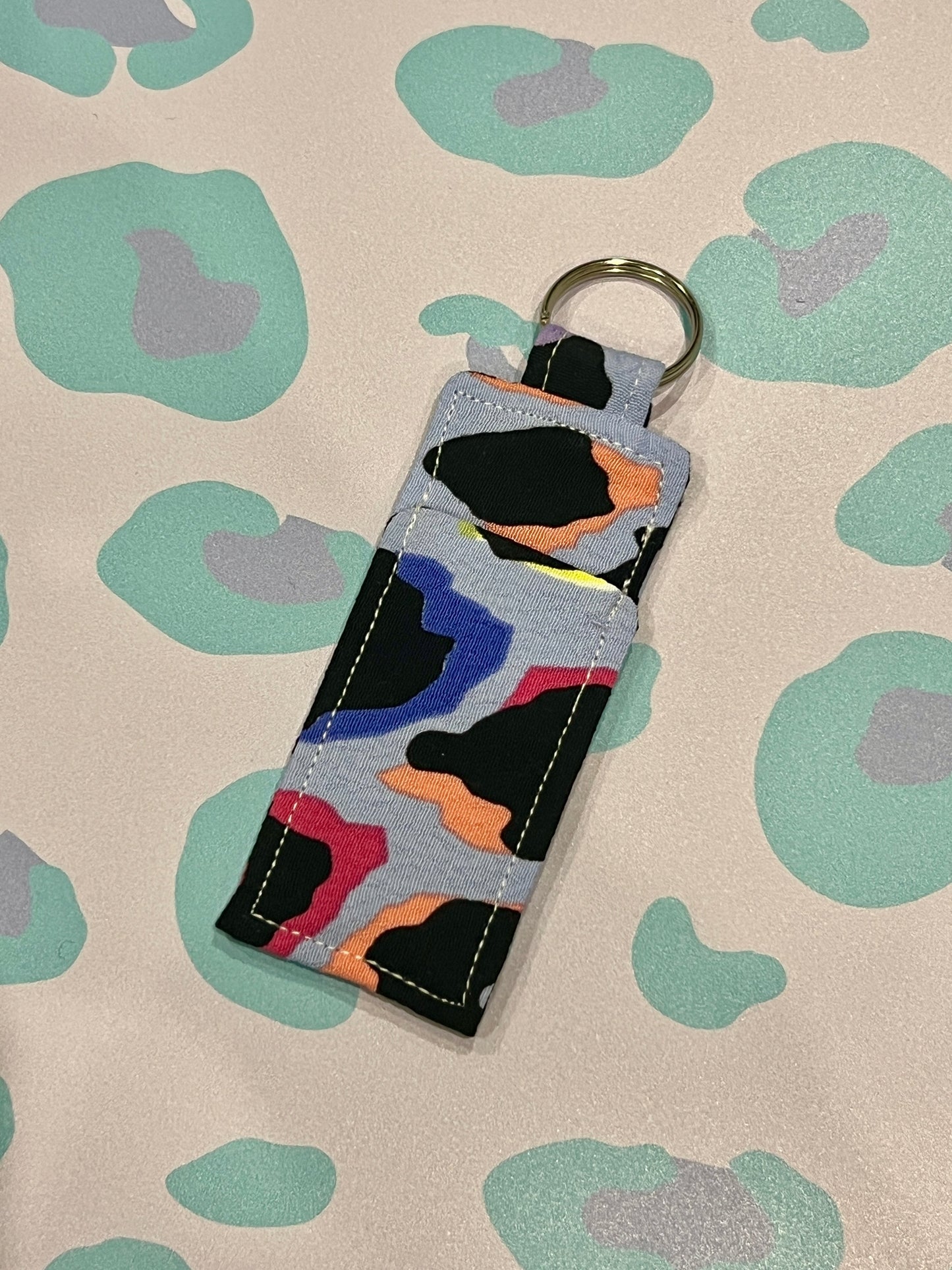Sew Much Love blue rainbow leopard print lip balm holder with keyring. Handmade fabric accessory.