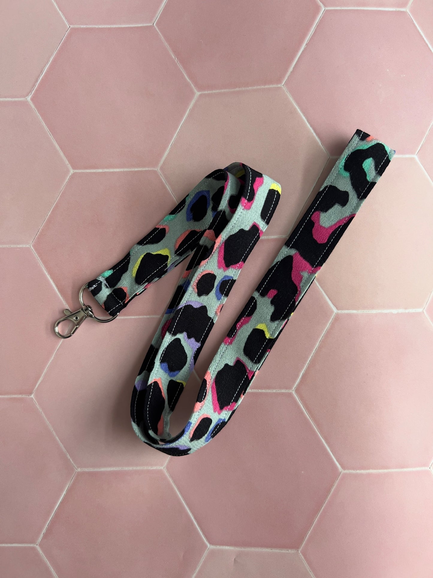 Sew Much Love khaki lanyard with a rainbow leopard print and silver clip. Features black, pink, yellow, blue, and teal accents.