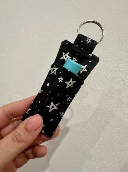 Keychain with star pattern and blue lip balm inside, held by a hand against a neutral background