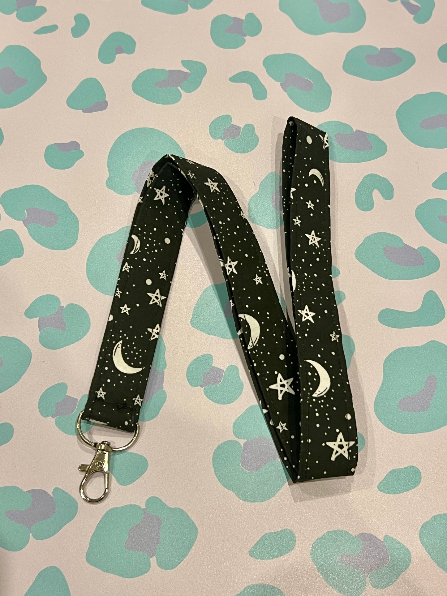 Black lanyard with star and moon pattern on a patterned background