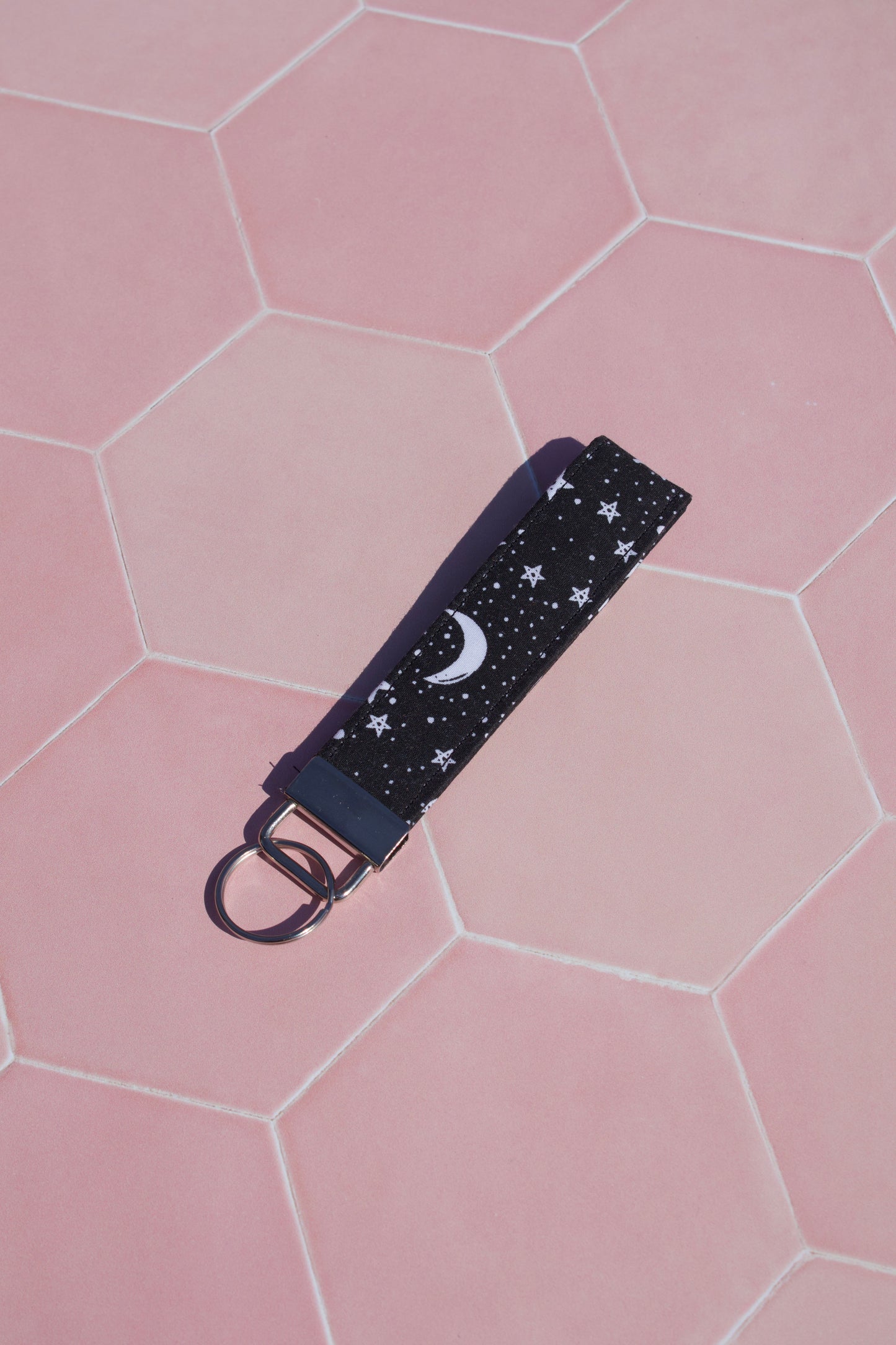 Keychain with star and moon pattern on a pink hexagonal tiled background