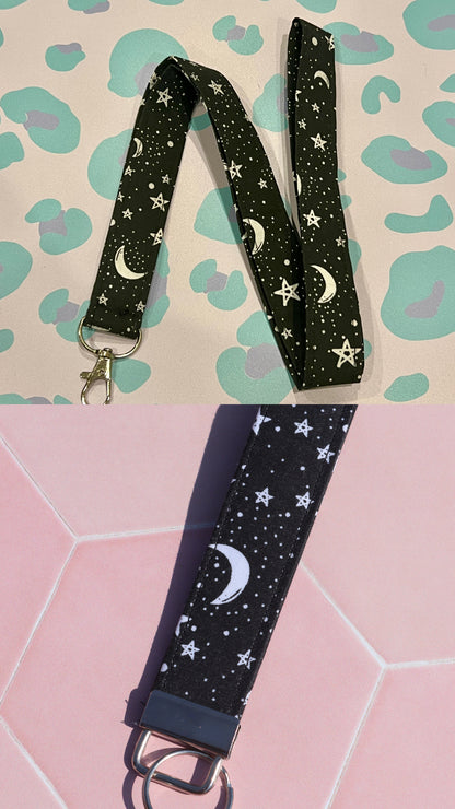 Black lanyard with star and moon pattern on a pink and green patterned background