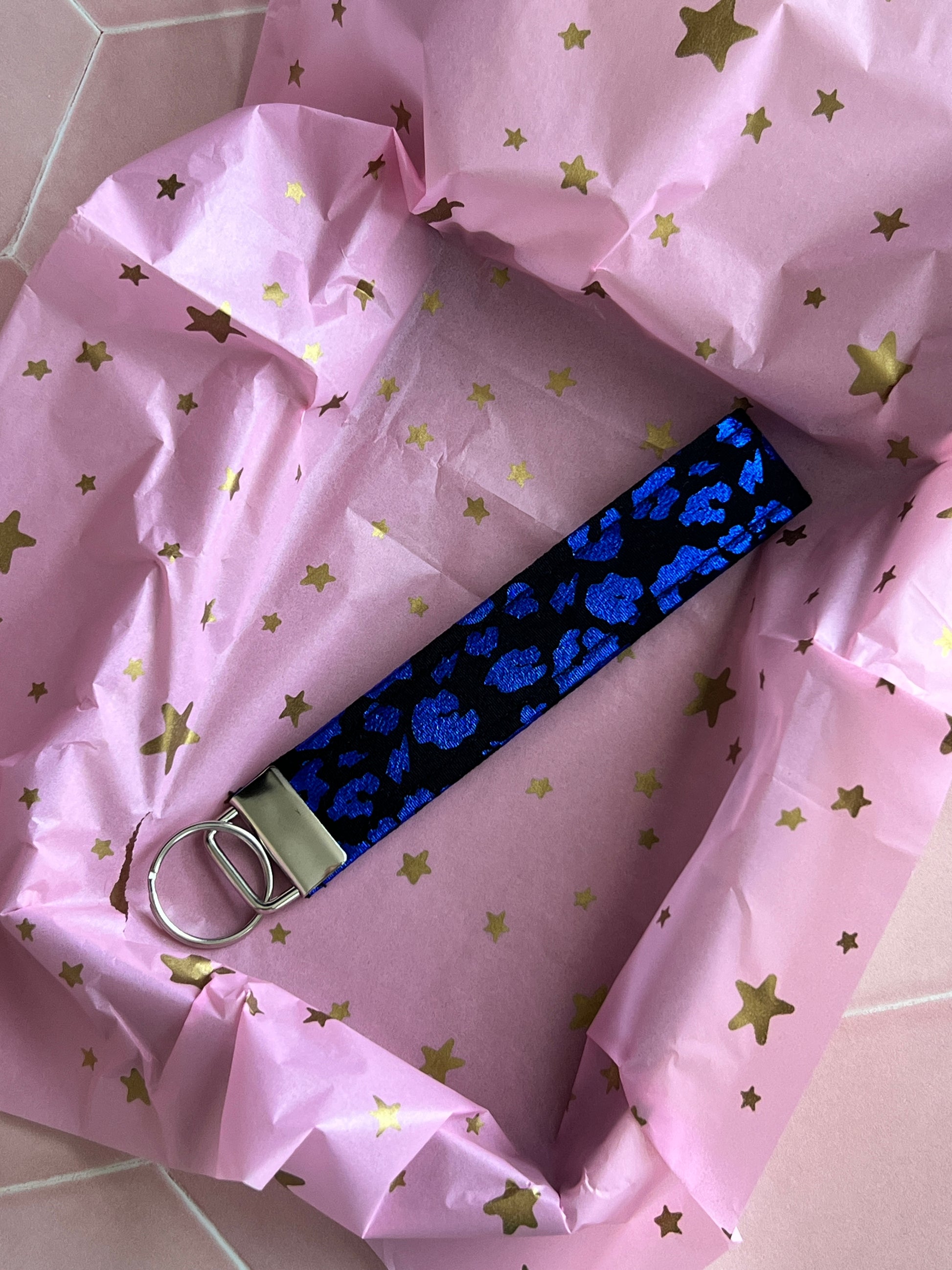 Gift-wrapped handmade black and blue foil leopard print wristlet keychain, displayed on pink star tissue paper, eco-friendly small business packaging UK