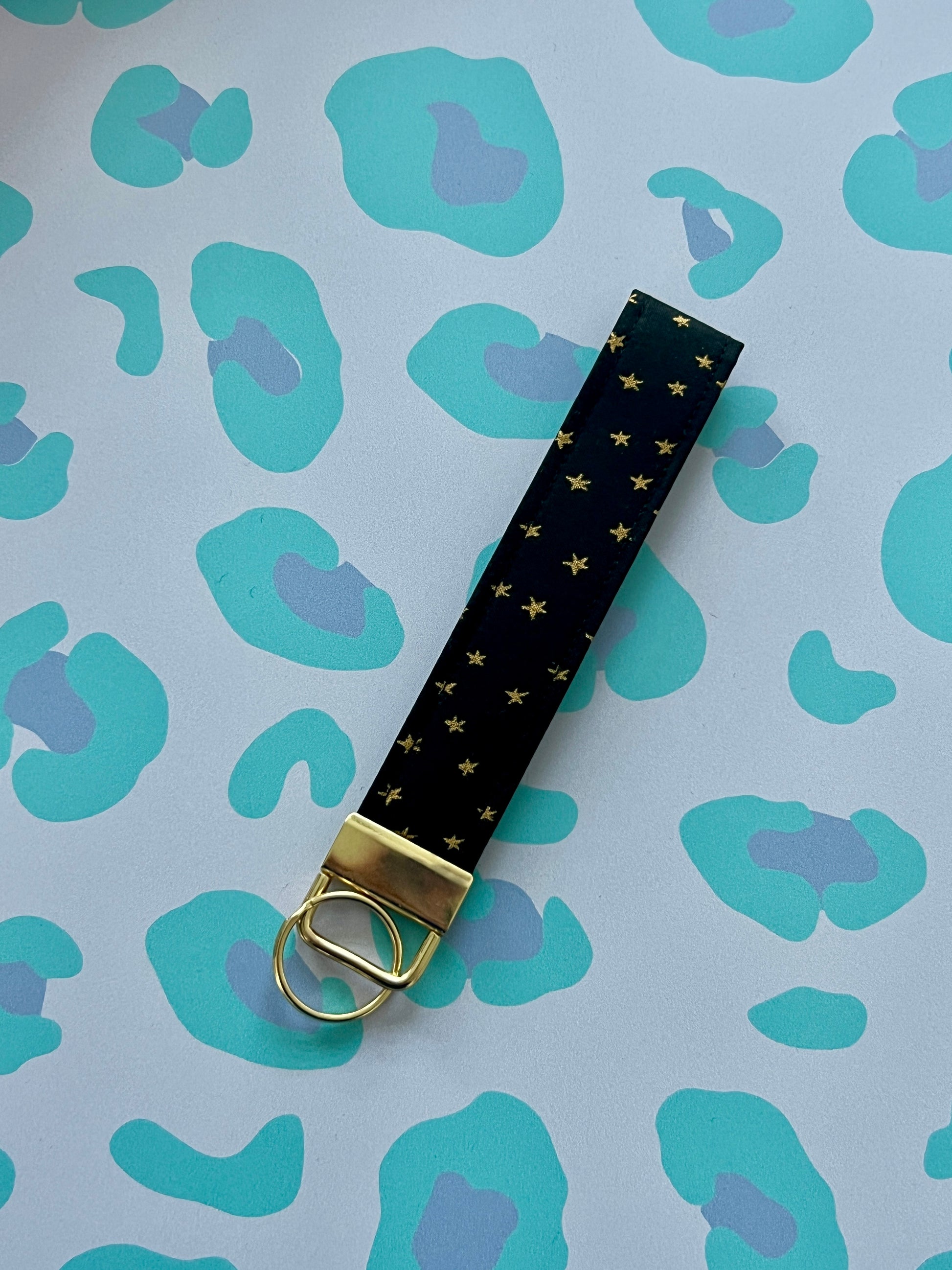 Black keychain with gold accents on a blue patterned background