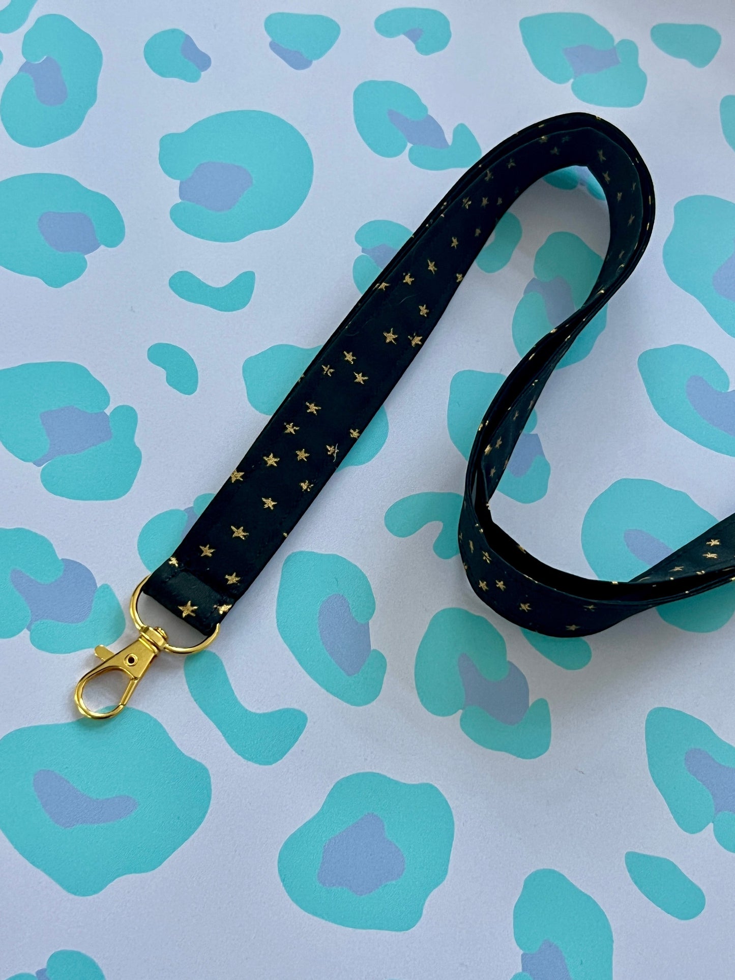 Sew Much Love black fabric lanyard with gold stars and a gold lobster clasp.