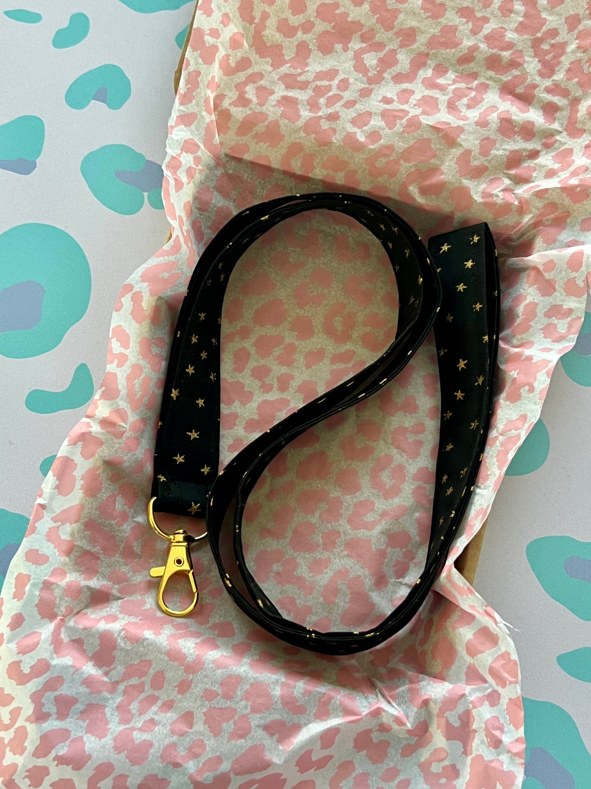 Sew Much Love black fabric lanyard with gold stars and a gold lobster clasp.