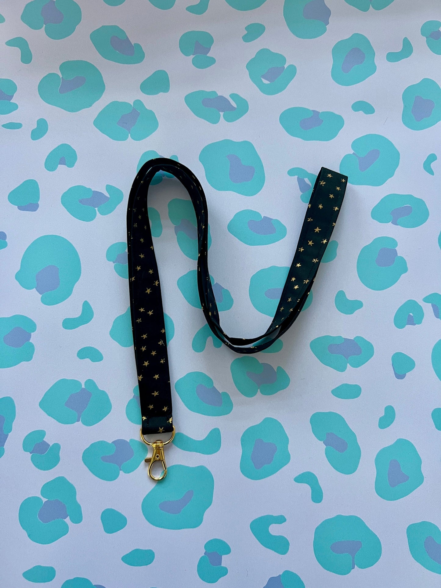 Sew Much Love black fabric lanyard with gold stars and a gold lobster clasp.