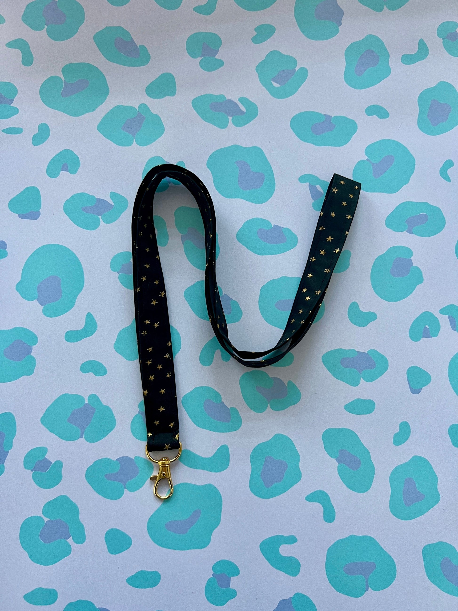 Sew Much Love black fabric lanyard with gold stars and a gold lobster clasp.