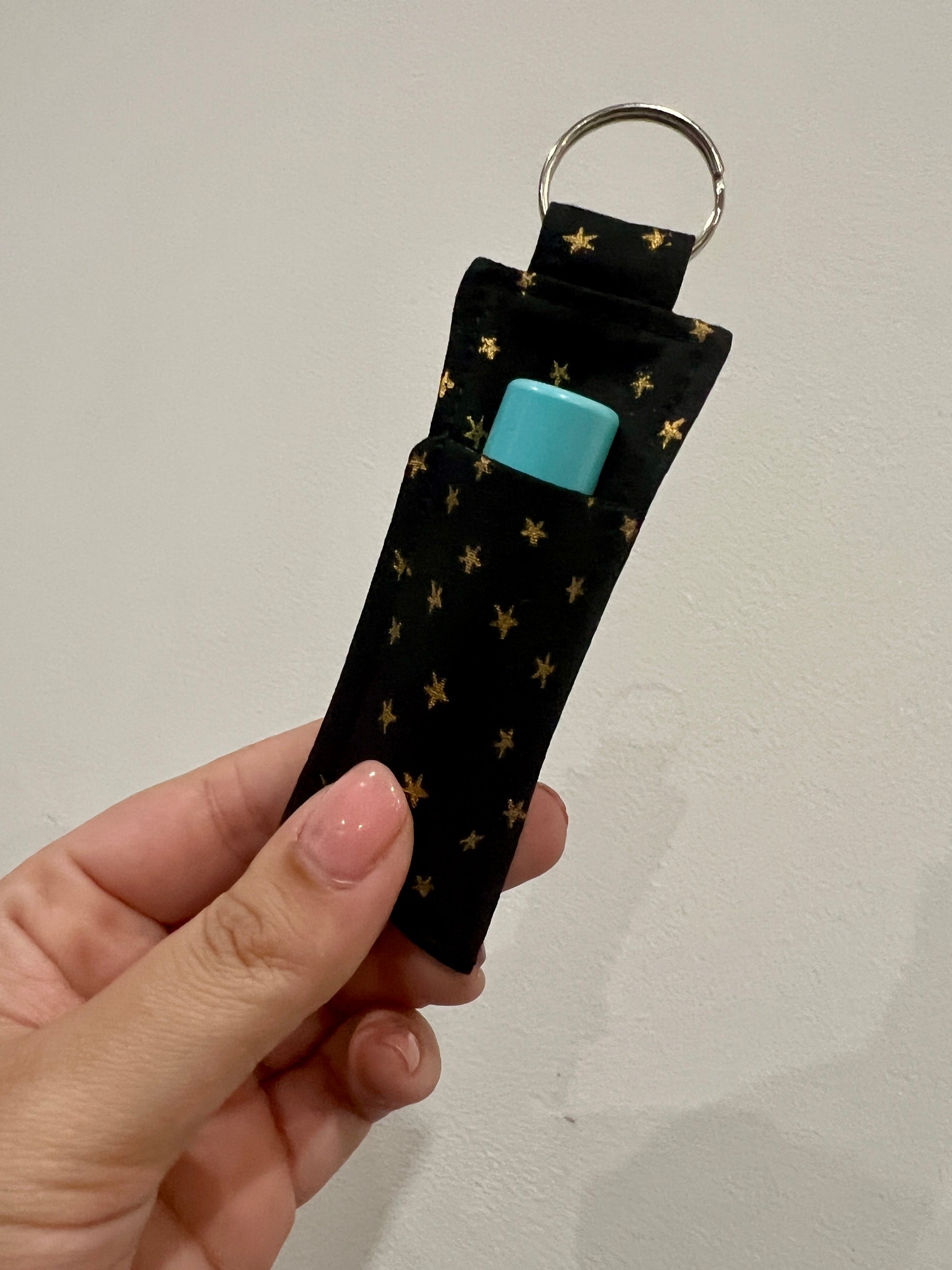 Keychain with star pattern and a lip balm inside held by a hand against a plain background