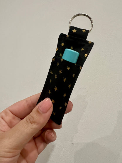 Keychain with star pattern and a lip balm inside held by a hand against a plain background