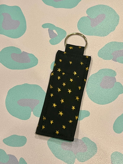 Black keychain with gold stars on a patterned background