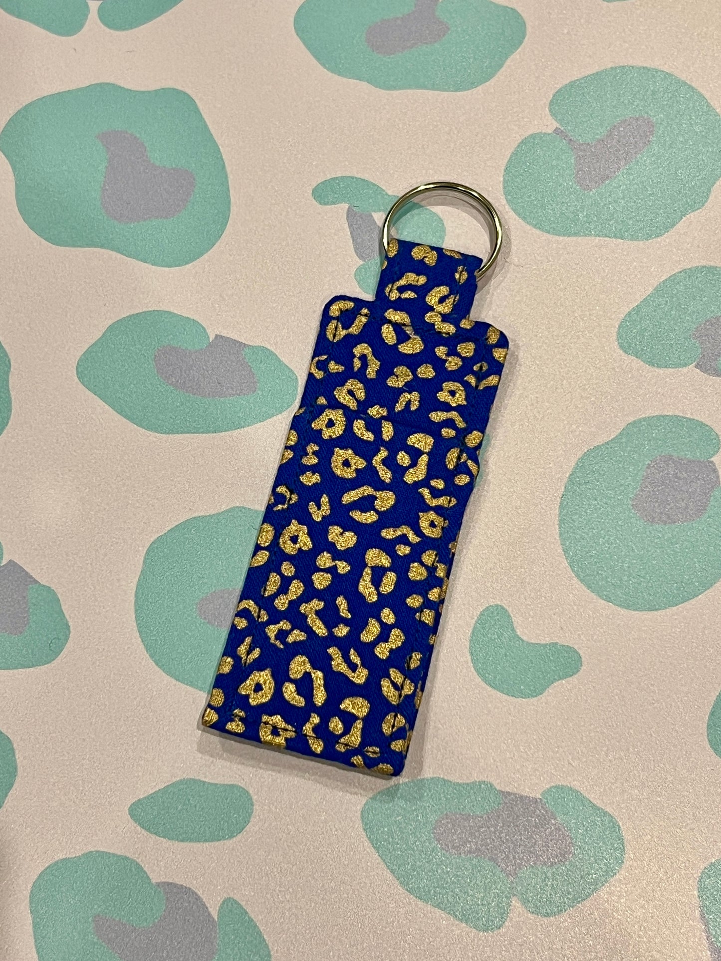 Blue keychain with yellow leopard print on a patterned background