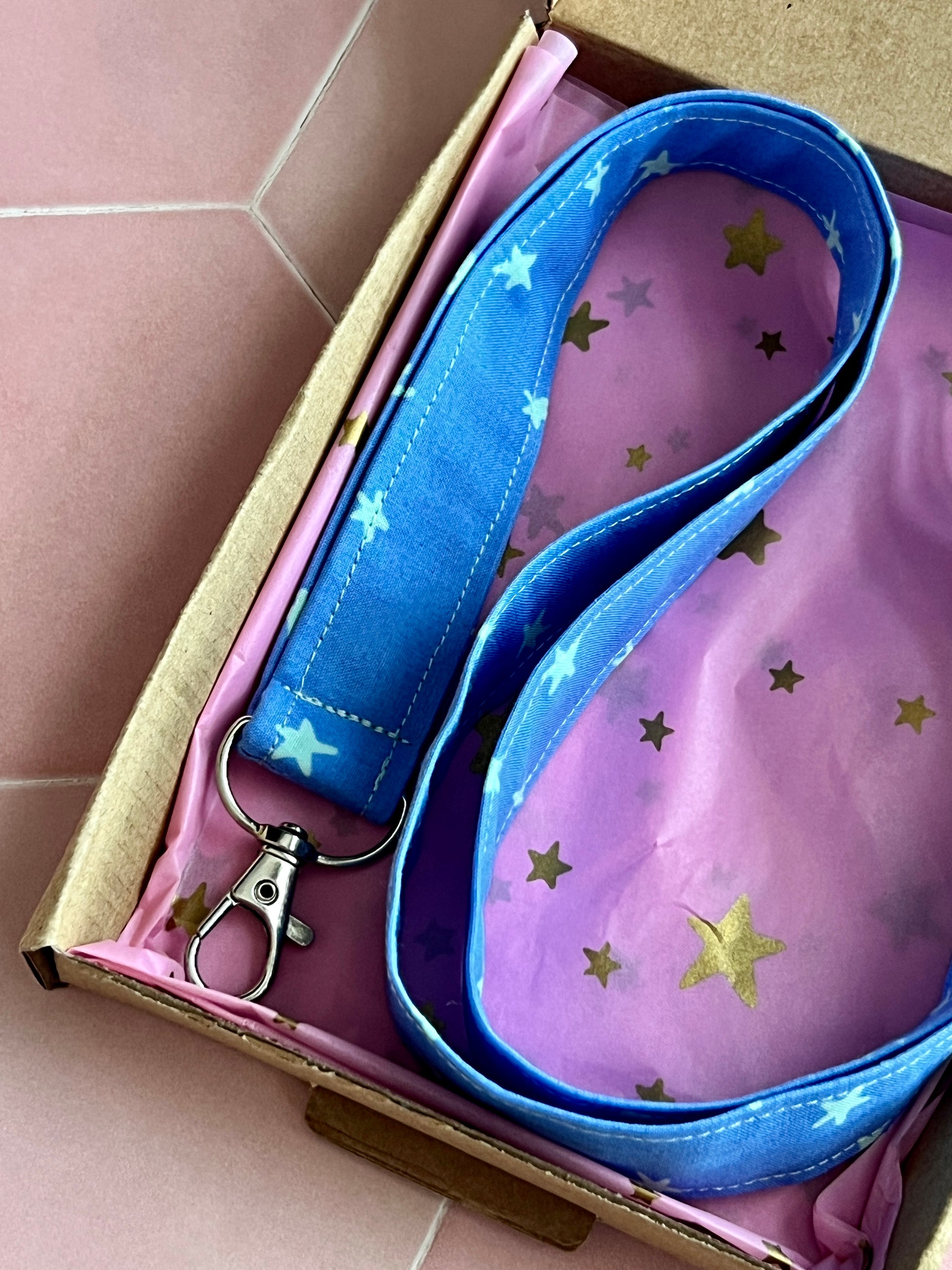 Blue fabric lanyard with mint coloured stars, D-ring key holder, displayed in pink and gold starry tissue paper gift packaging