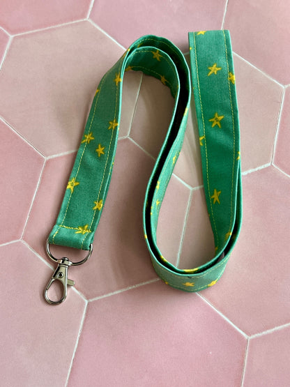 Sew Much Love green fabric lanyard with yellow stars and silver D-ring clasp for keys and ID badges.