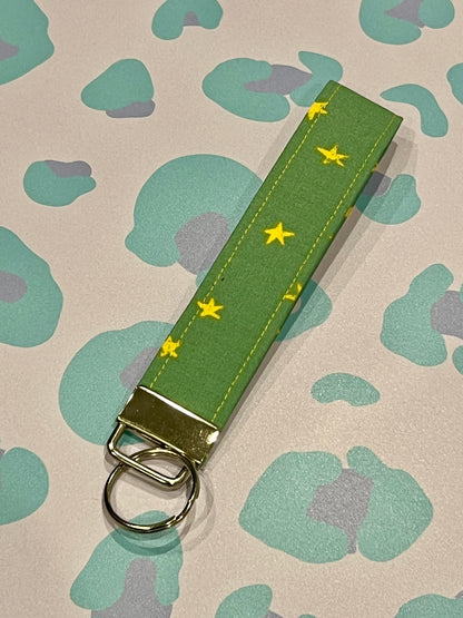 Sew Much Love green fabric wristlet keychain with yellow stars and silver clasp.