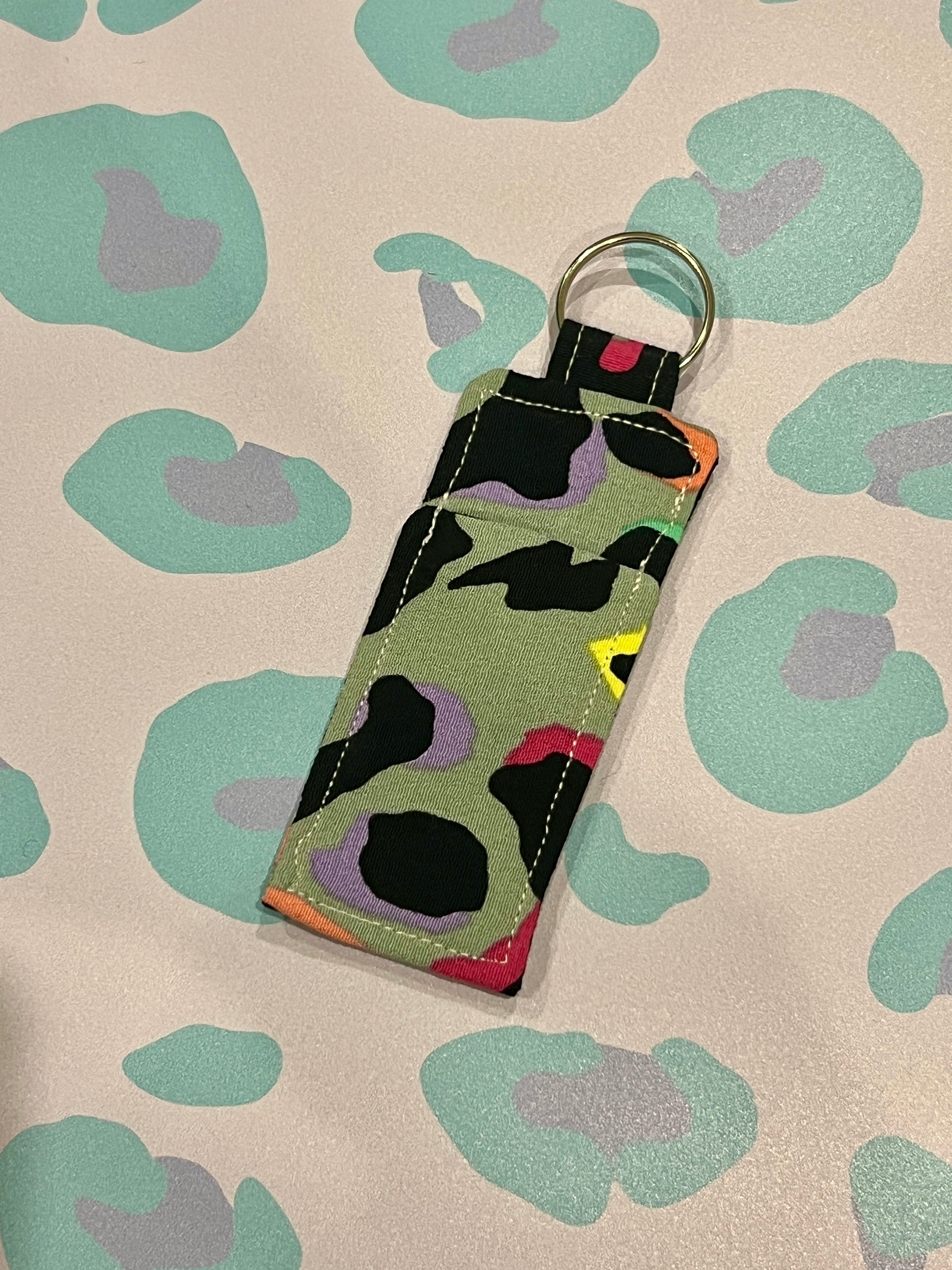 Keychain with colorful abstract pattern on a beige background with green floral designs