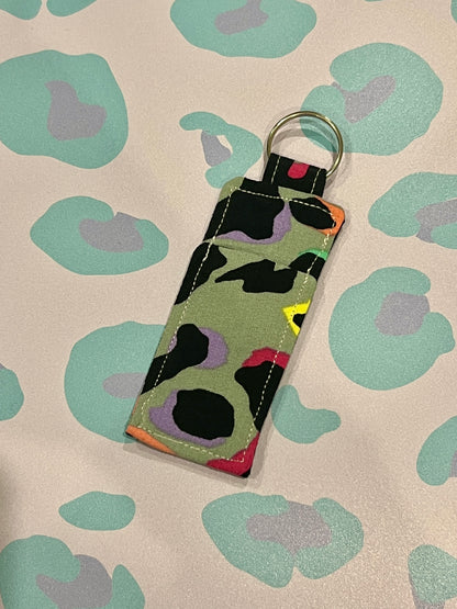 Keychain with colorful abstract pattern on a beige background with green floral designs