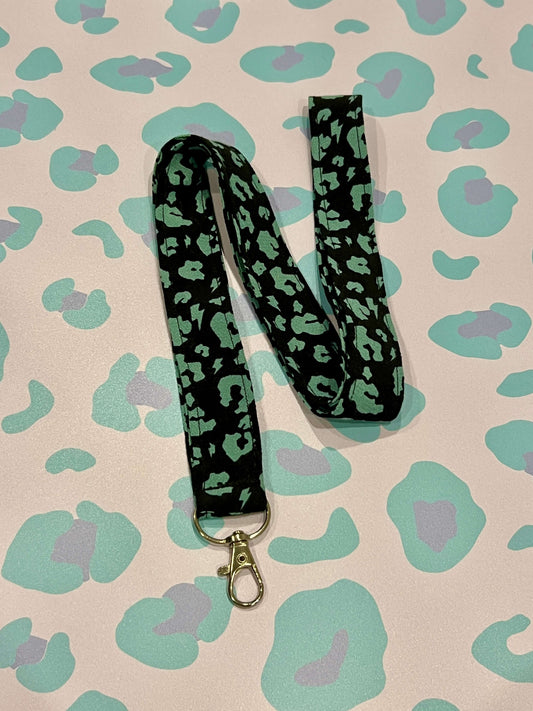 Green and black leopard print lanyard on a patterned background
