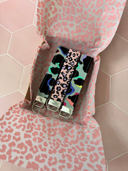 2 Khaki Rainbow Leopard Print Wristlet Keychain with a purple and pink wristlet keychain in a packaging box