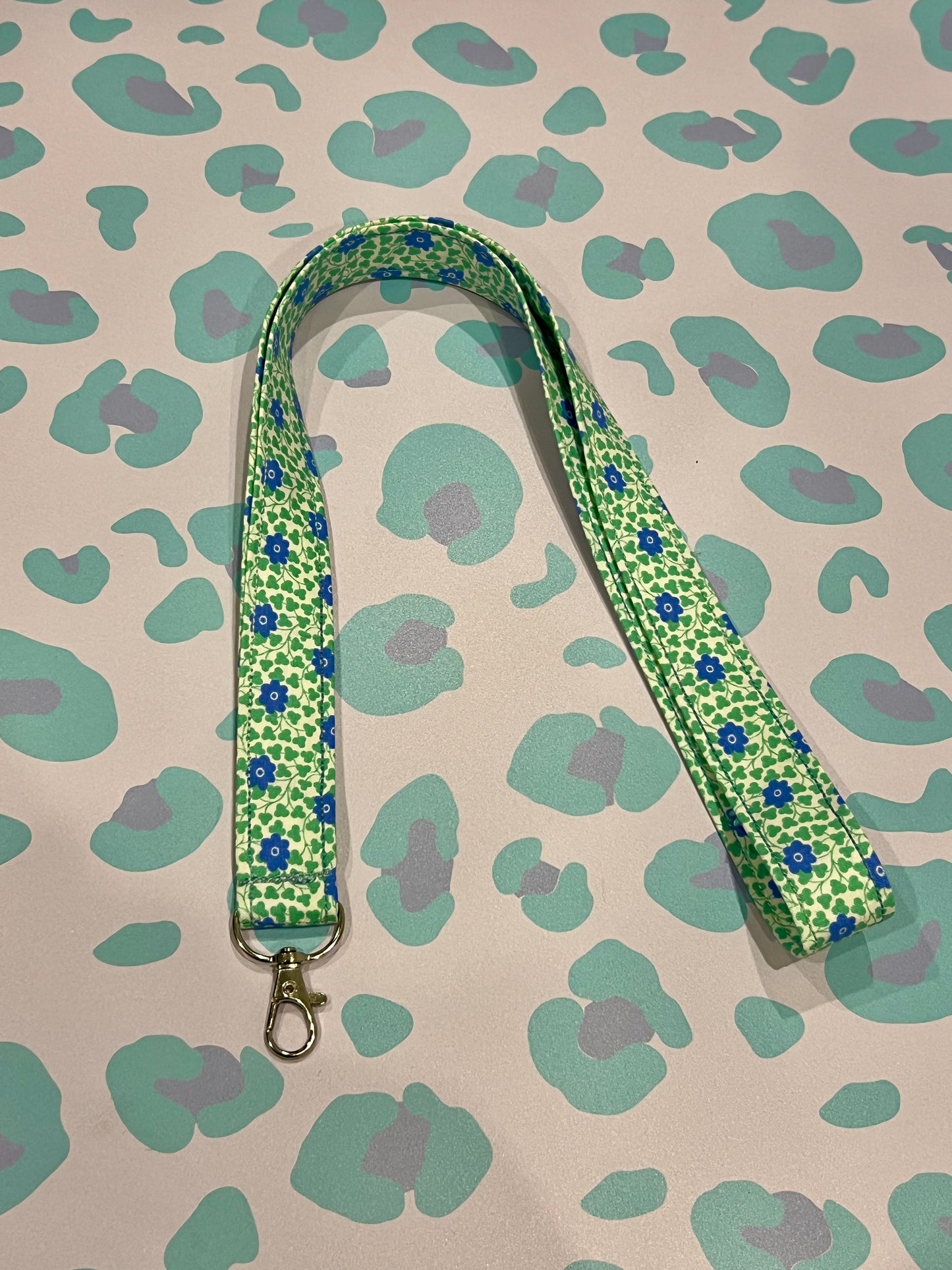 Green floral patterned lanyard on a patterned background