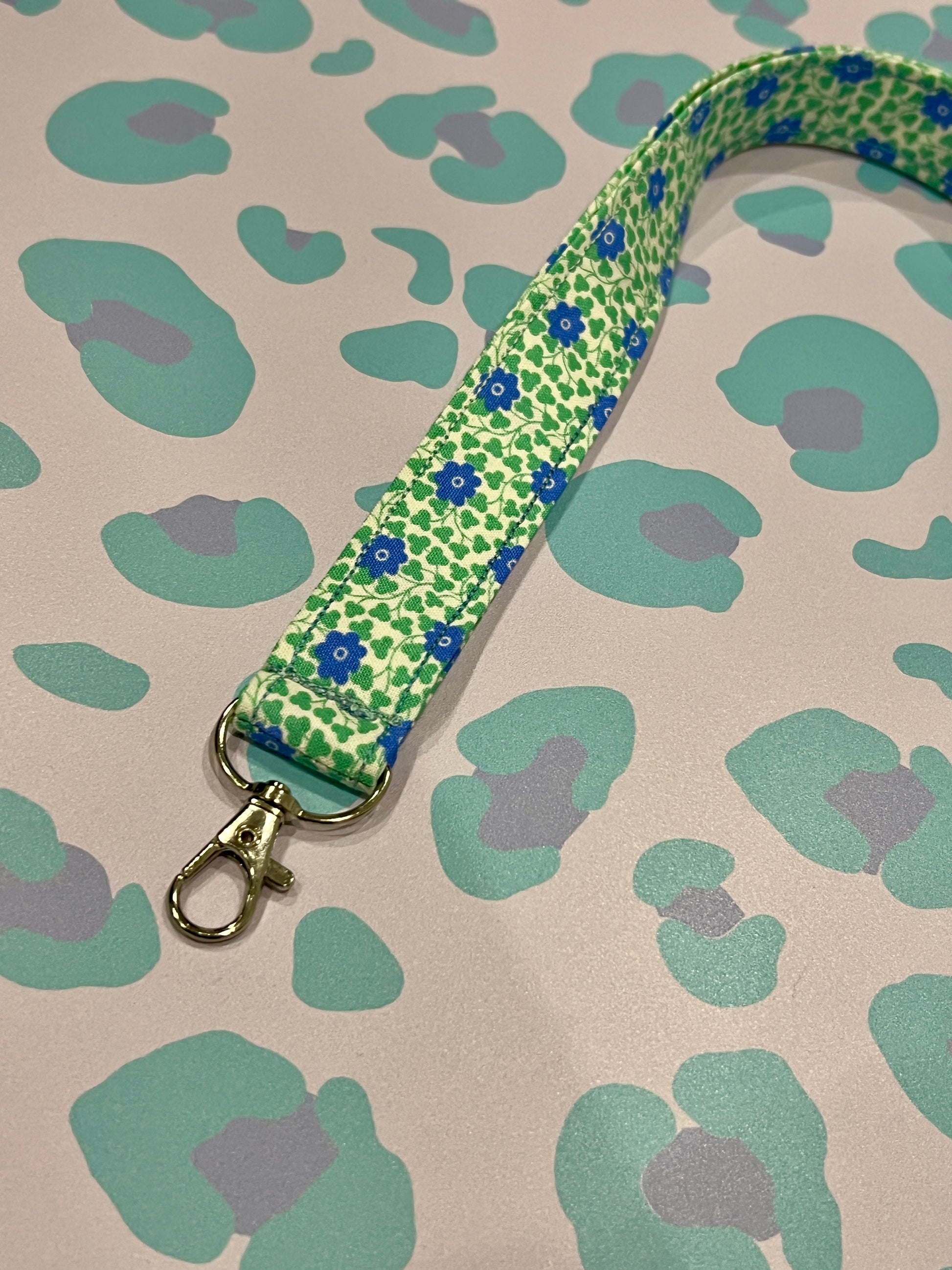 Green floral patterned lanyard on a beige background with green and purple leopard print