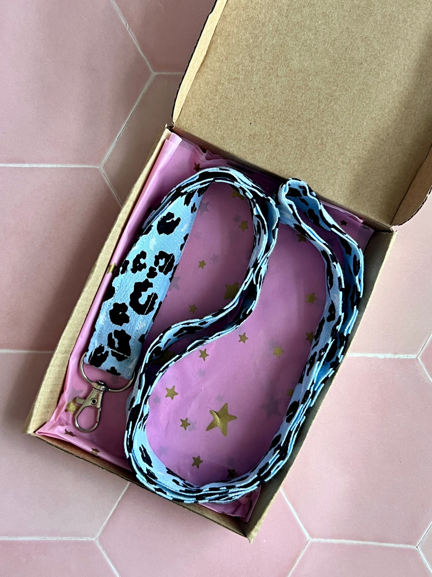Handmade light blue leopard print fabric lanyard with D-ring, wrapped in pink starry tissue paper, eco-friendly packaging