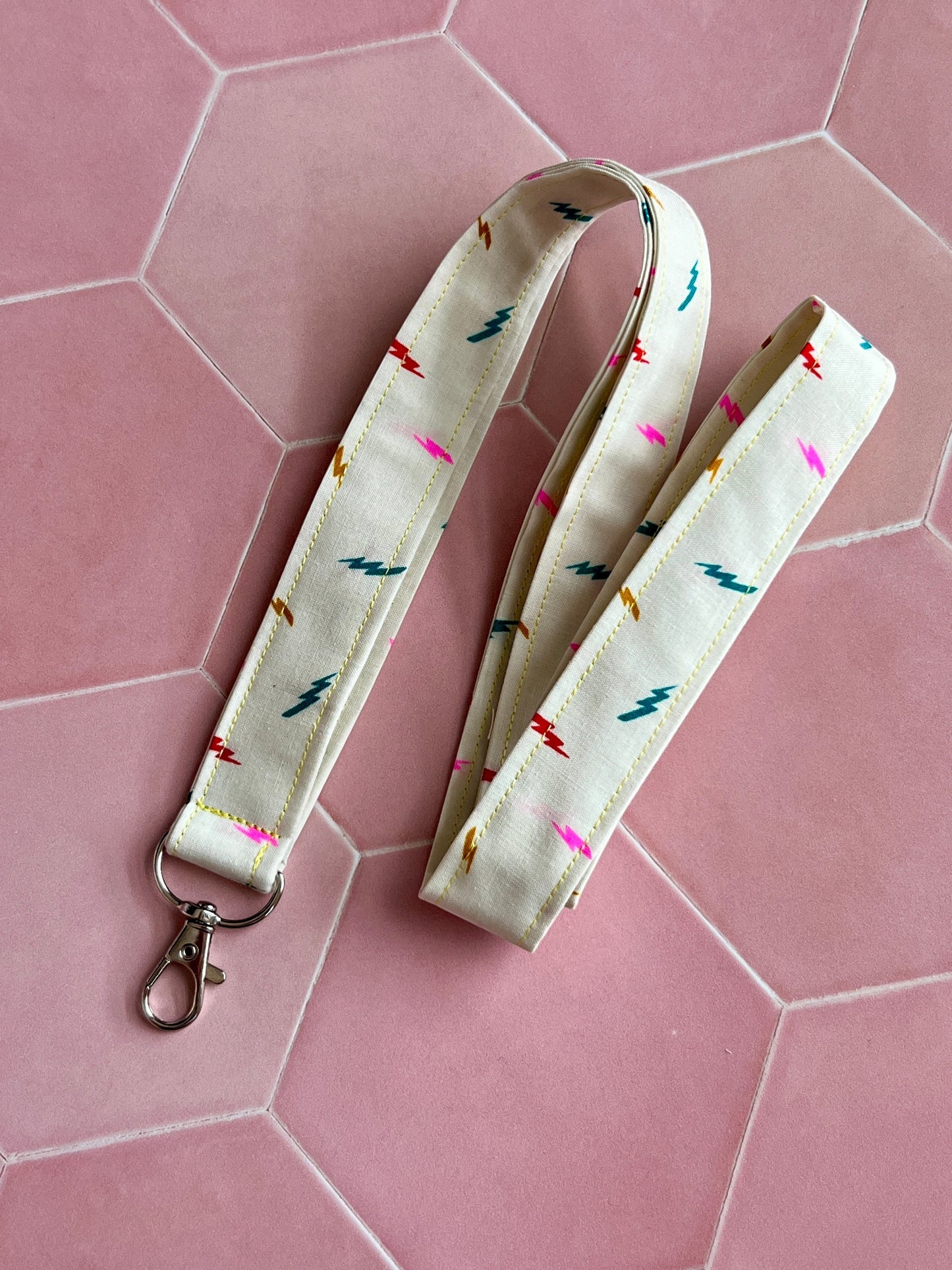 Sew Much Love cream fabric lanyard with colourful lightning bolt print and silver D-ring clasp.
