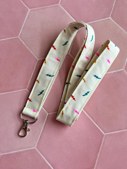 Sew Much Love cream fabric lanyard with colourful lightning bolt print and silver D-ring clasp.