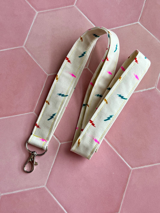 Sew Much Love cream fabric lanyard with colourful lightning bolt print and silver D-ring clasp.