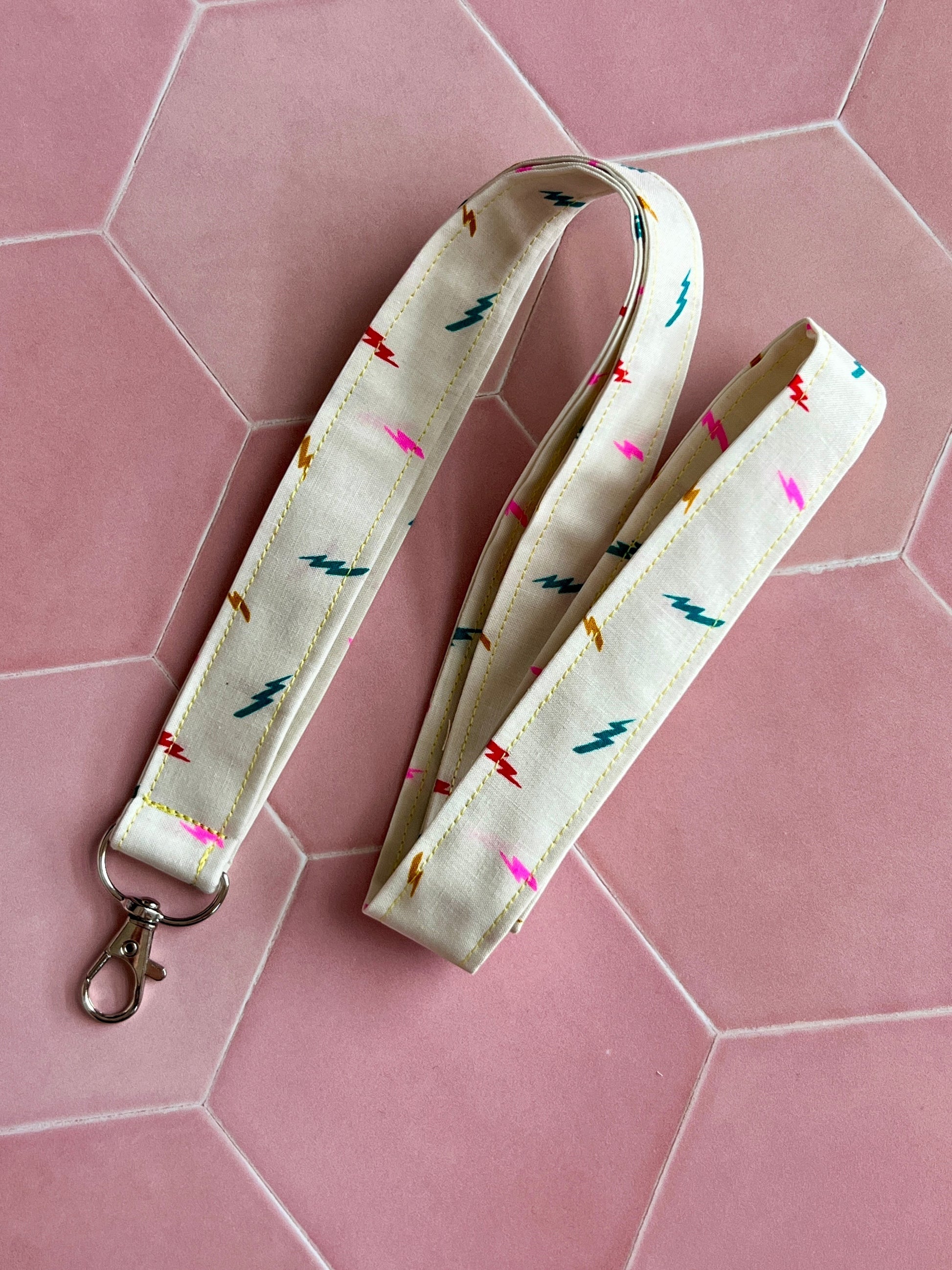 Sew Much Love cream fabric lanyard with colourful lightning bolt print and silver D-ring clasp.