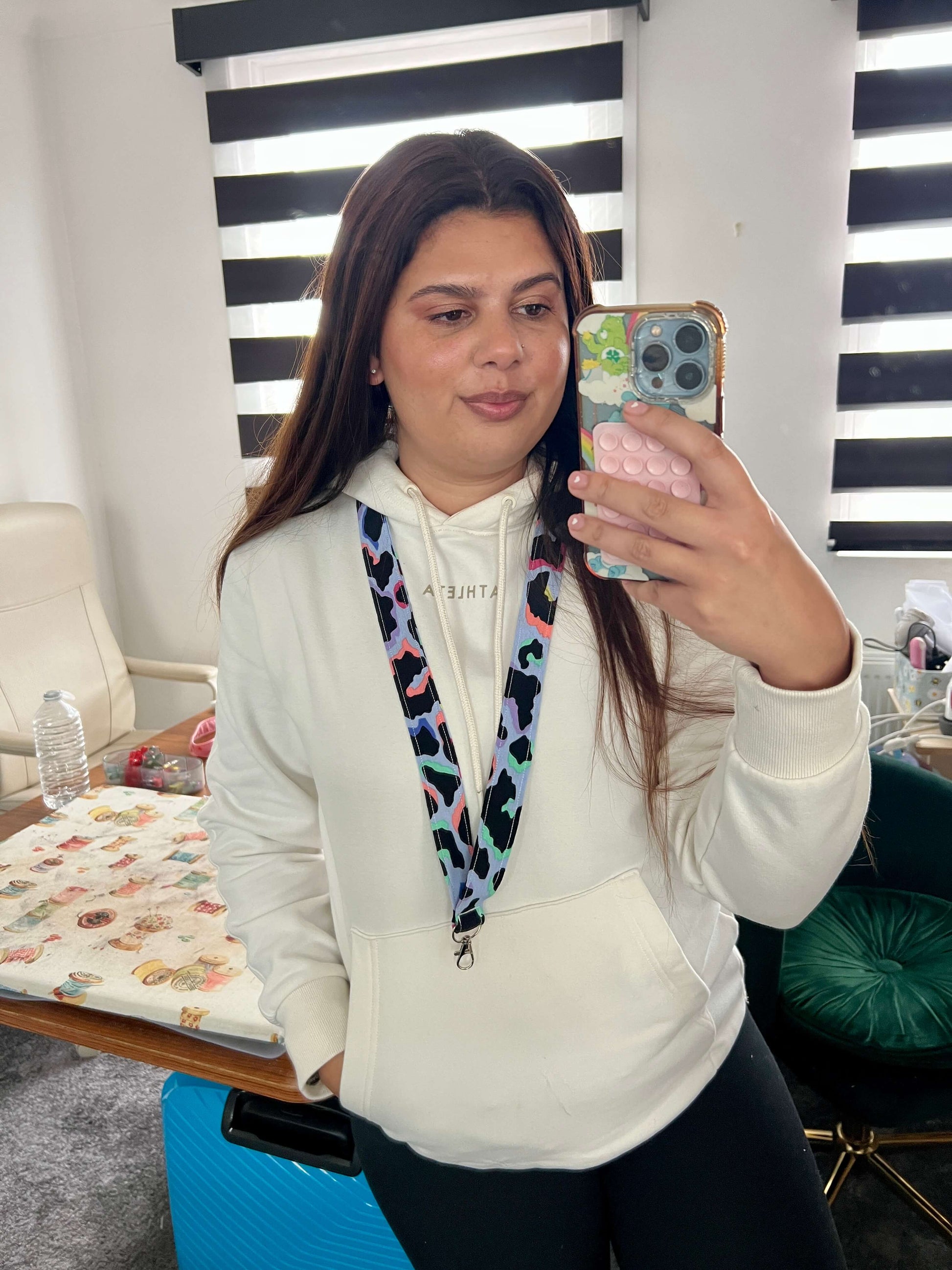 Brand owner Elana taking a mirror selfie wearing a white hoodie with a colourful Light Blue Rainbow Leopard Print Lanyard