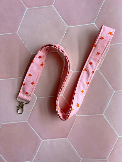 Sew Much Love pink fabric lanyard with orange stars and a silver D-ring clasp for keys or ID badges.
