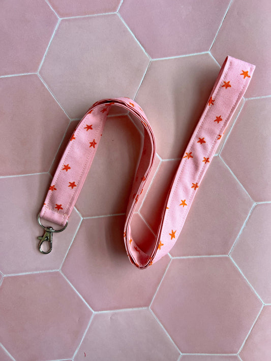 Sew Much Love pink fabric lanyard with orange stars and a silver D-ring clasp for keys or ID badges.