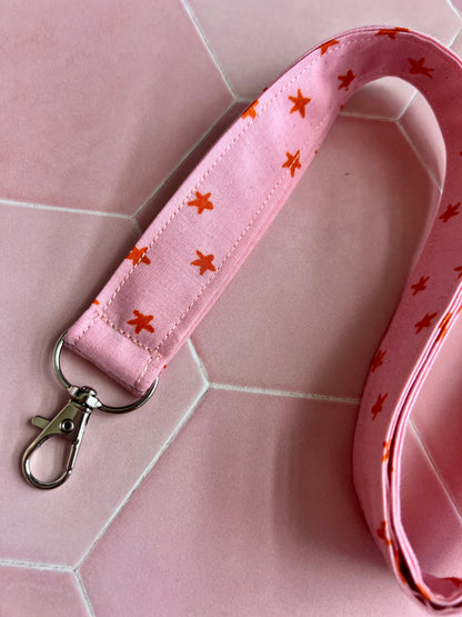 Close-up of pink and orange star print lanyard with secure D-ring attachment, perfect for teachers, students, and busy professionals