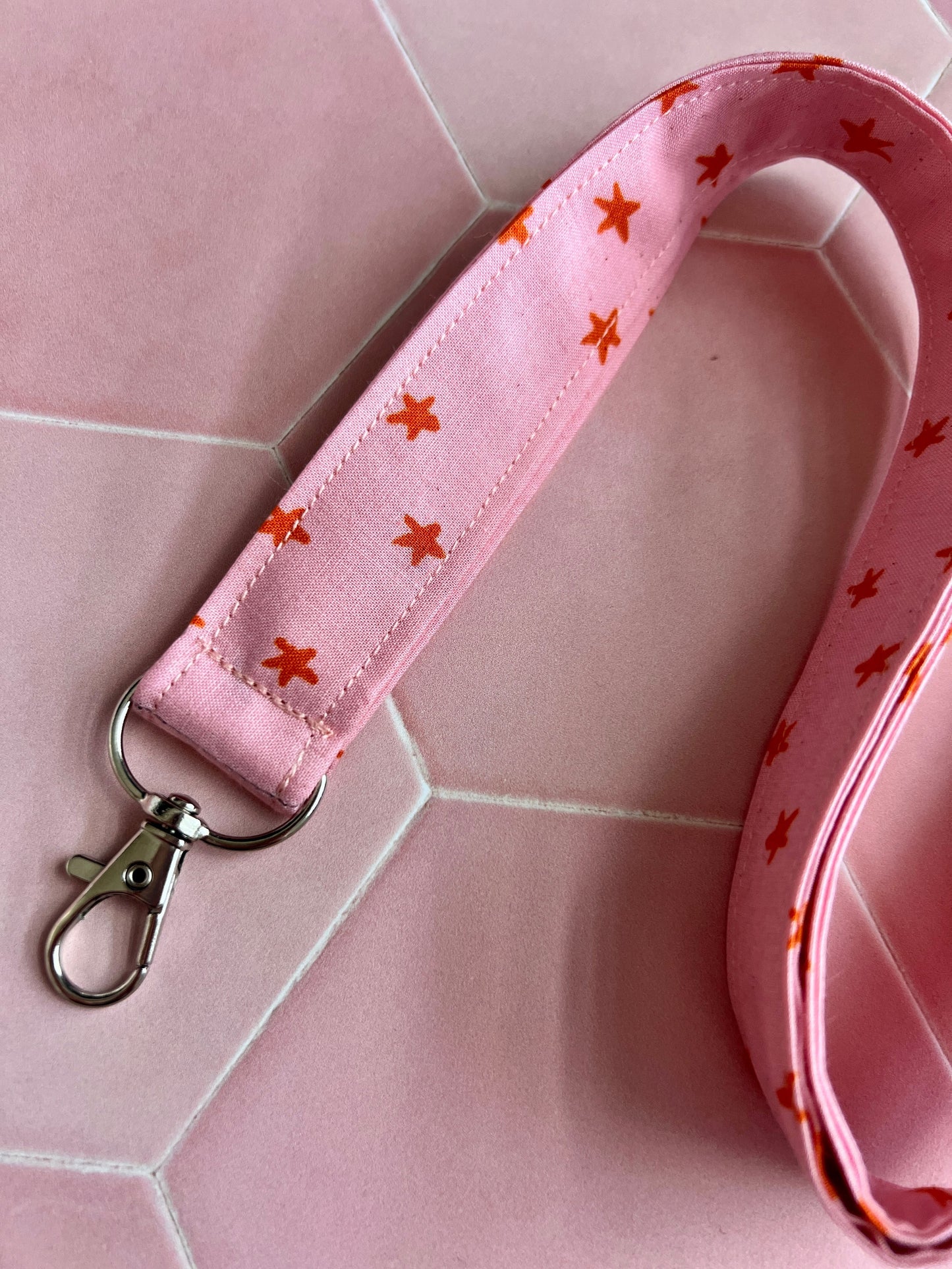 Sew Much Love pink fabric lanyard with orange stars and a silver D-ring clasp for keys or ID badges.