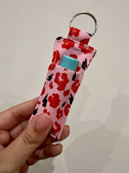 Keychain with red leopard pattern with lip balm on a plain background