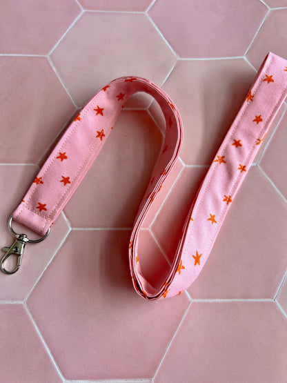 Sew Much Love pink fabric lanyard with orange stars and a silver D-ring clasp for keys or ID badges.