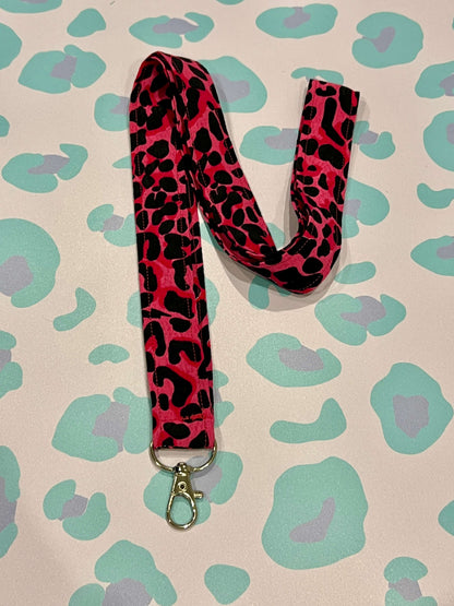 Pink and black leopard print lanyard on a leopard print background