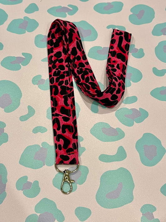 Pink and black leopard print lanyard on a leopard print background