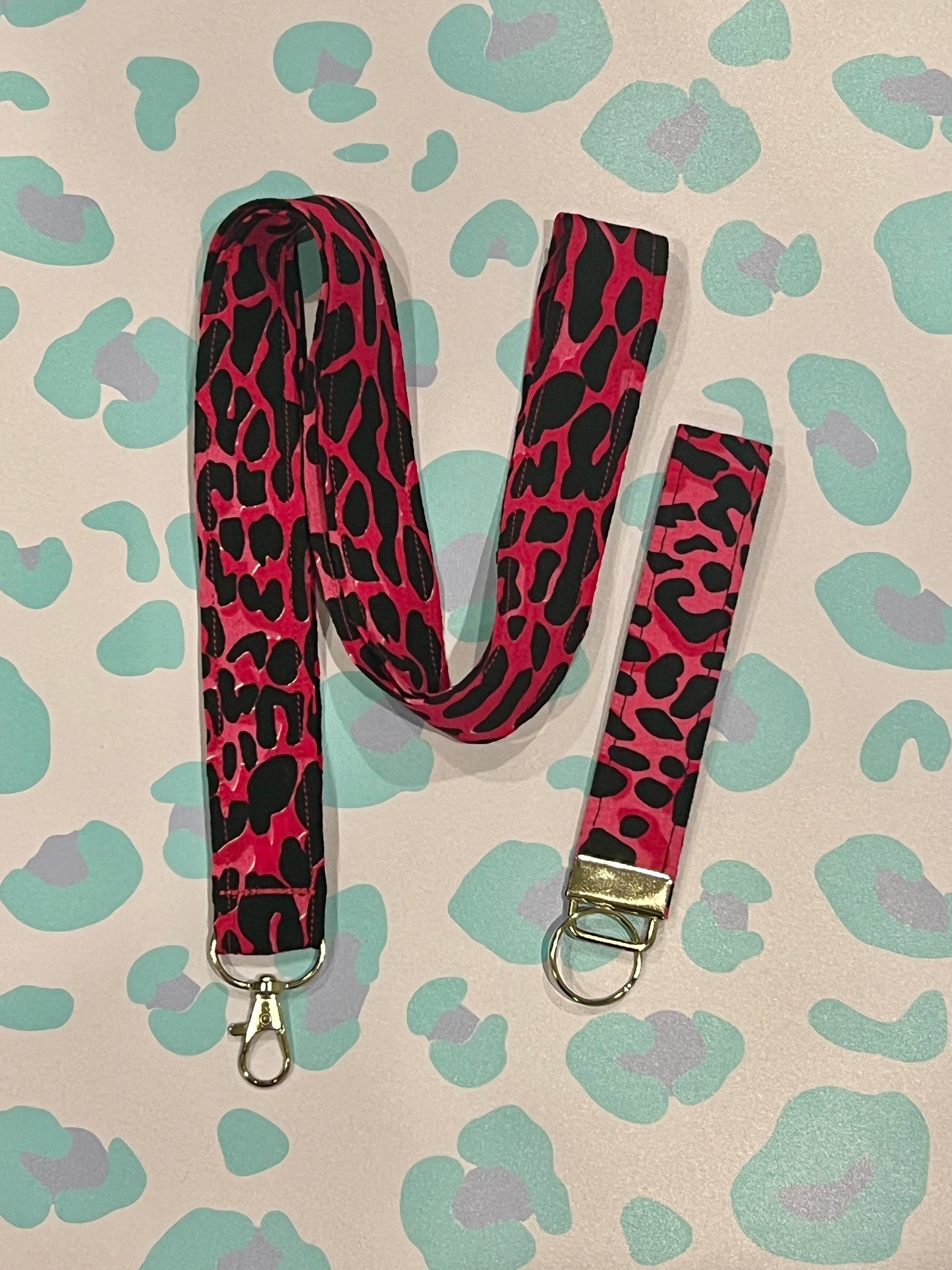 Pink and black leopard print lanyard with keychain on a patterned background