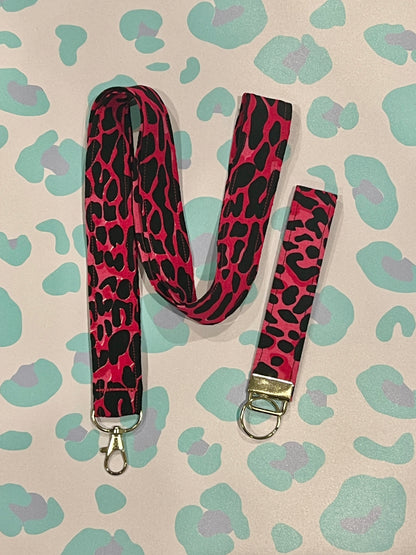 Pink and black leopard print lanyard with keychain on a patterned background