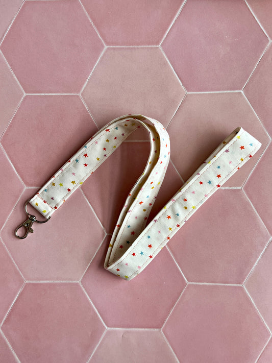 Handmade fabric lanyard with D-ring, featuring a cream background and multicoloured mini star print, ideal for keys and ID badges, small business accessories UK.