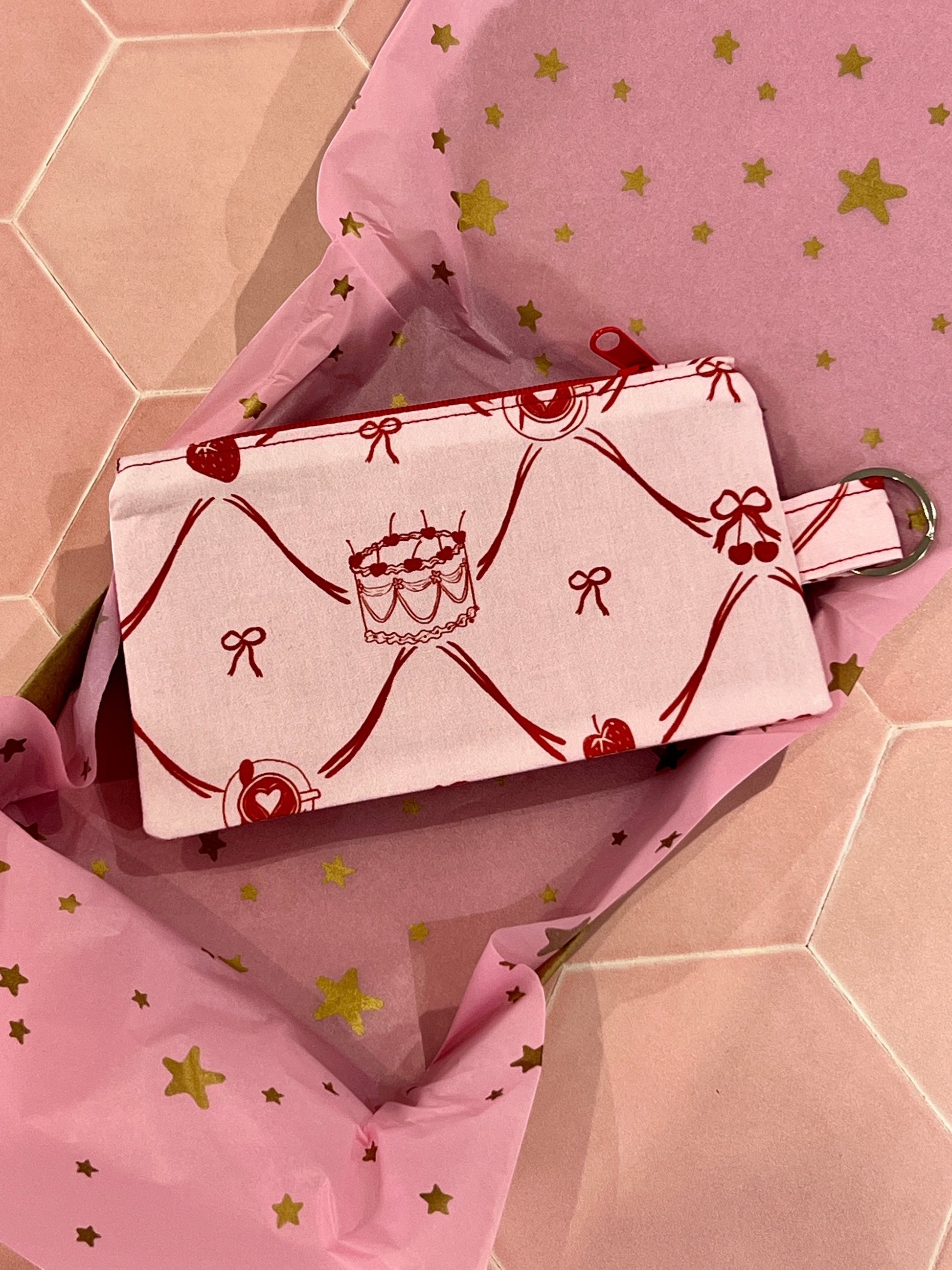 Sew Much Love pink fabric coin purse with red cake, strawberry, and bow print. Features keyring attachment.
