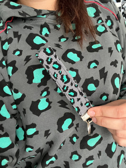 Sew Much Love grey wristlet keychain with black and teal snow leopard print and lightning bolts.