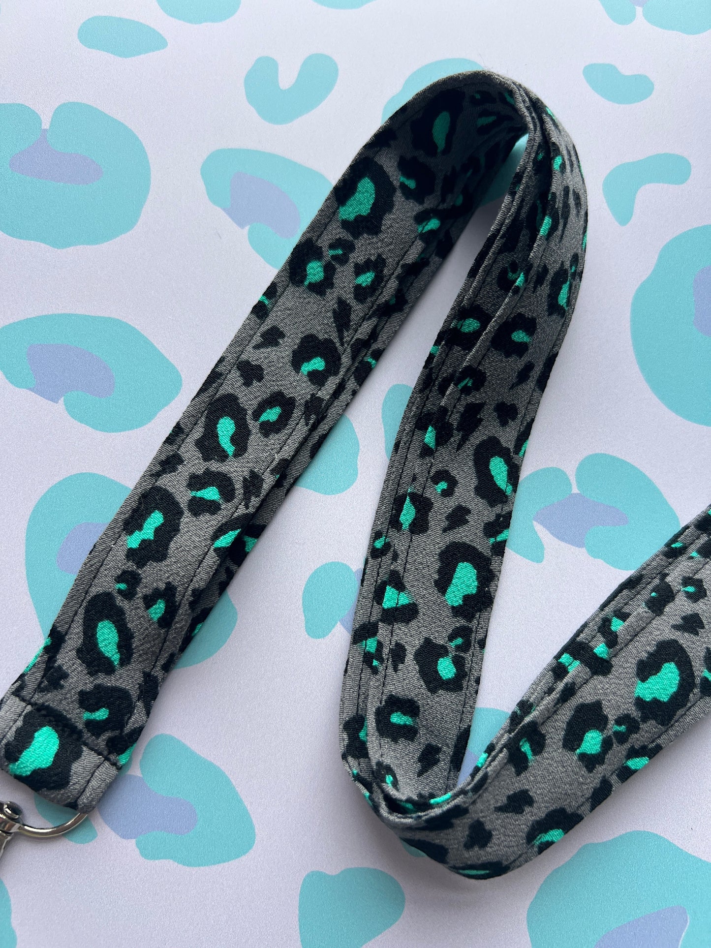 Sew Much Love grey fabric lanyard with black and teal snow leopard print and metal D-ring.
