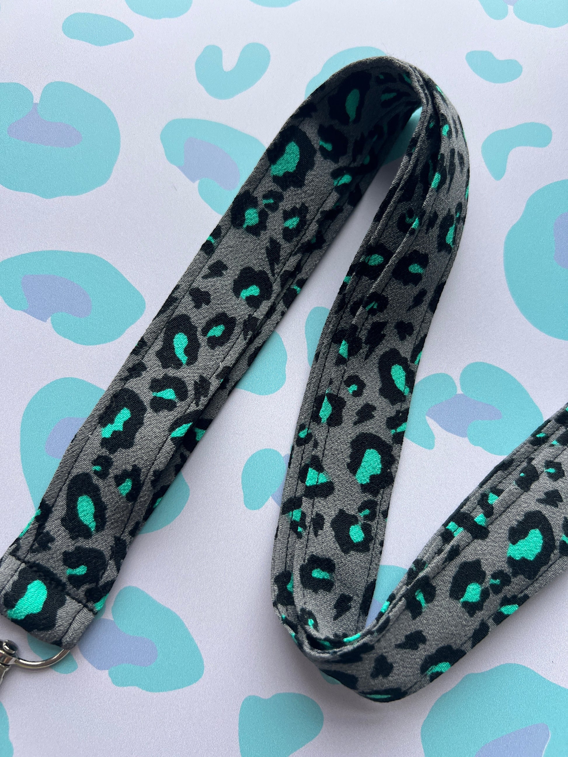 Sew Much Love grey fabric lanyard with black and teal snow leopard print and metal D-ring.