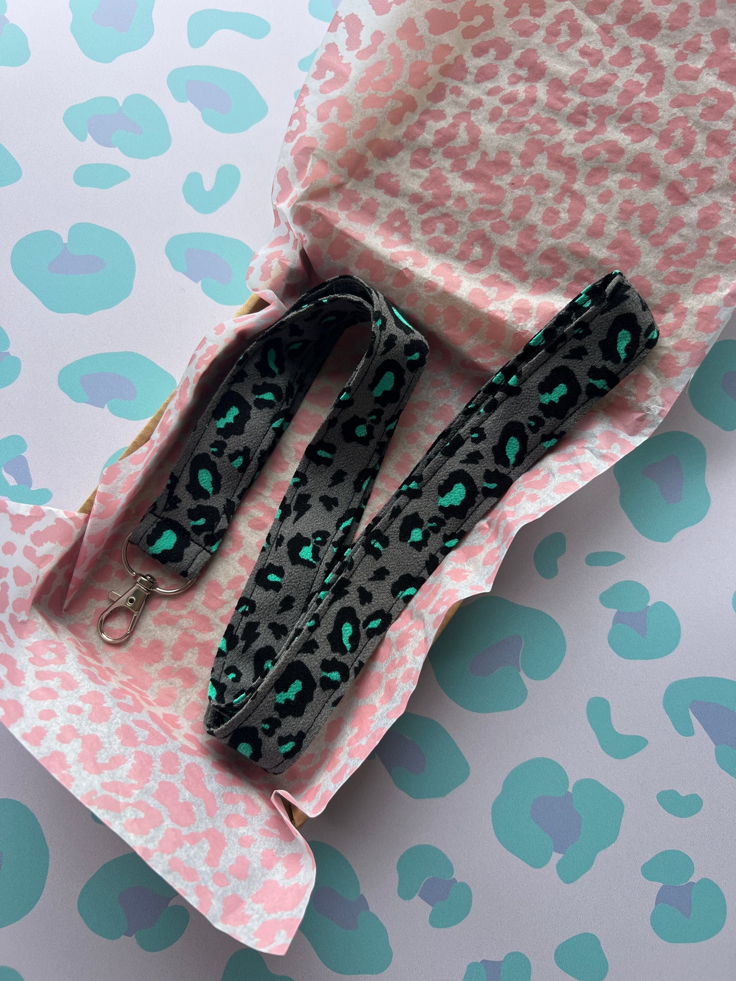 Sew Much Love grey fabric lanyard with black and teal snow leopard print and silver D-ring.